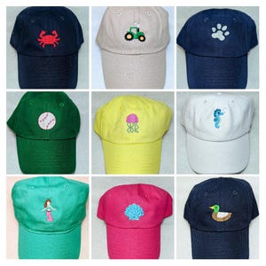 May include: Nine baseball caps in various colors, each embroidered with a different design. The designs include a crab, tractor, paw print, baseball, jellyfish, seahorse, mermaid, seashell, and a duck. The caps are made of a soft fabric.