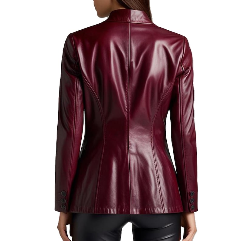 May include: A burgundy leather blazer with a stand-up collar and long sleeves. The back view shows a tailored fit with button details on the cuffs. The jacket is a deep red color.