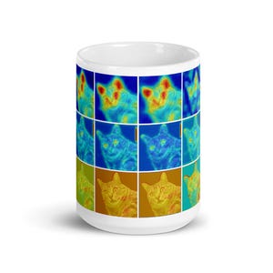 May include: A white ceramic mug featuring a colourful image of a cat's face repeated in a grid pattern. The cat's face is in shades of blue, yellow, and red.
