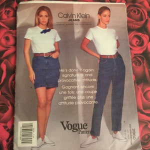 May include: A vintage Vogue sewing pattern for Calvin Klein Jeans. The pattern features two models wearing denim skirts and pants. The text on the pattern reads "He's done it again: signature fit and provocative attitude. Gagnant encore une fois: une coupe griffée plus une attitude provocante."