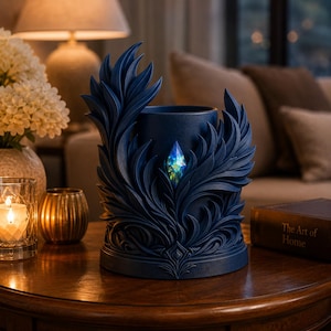 Op de afbeelding: Een donkerblauwe decoratieve kandelaar met een gedetailleerd, sierlijk ontwerp. De houder heeft een centrale opening en is versierd met gestileerde bladvormige elementen. Een veelkleurig kristal is in het midden geplaatst. De houder staat op een houten tafel.