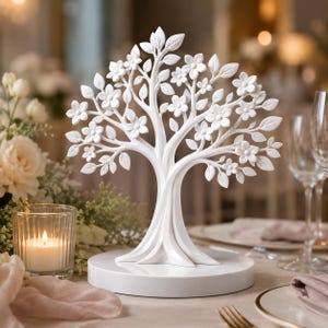 May include: A white decorative tree sculpture featuring intricate branches, numerous leaves, and small five-petaled flowers. The tree is mounted on a smooth, circular white base, creating a solid, monochromatic piece of home decor.