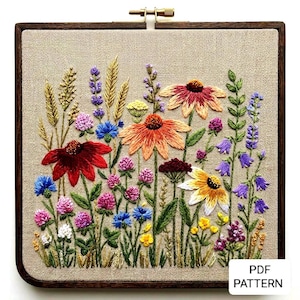May include: A colourful embroidered floral design, showcasing various wildflowers in shades of red, orange, yellow, blue, and purple. The embroidery is set within a square wooden frame, with a beige fabric backdrop. The text "PDF PATTERN" is visible in the bottom right.