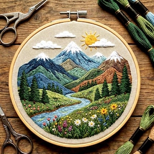 May include: An embroidered landscape scene in a wooden hoop. The artwork depicts mountains, a river, trees, and flowers, with a yellow sun and white clouds. Embroidery floss in various shades of green and blue is visible.