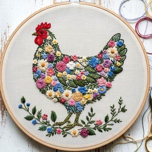 Peut inclure: Broderie d'un poulet dans un cercle en bois. Le poulet est rempli de fleurs colorées dans les tons de rose, bleu, jaune et blanc. Des feuilles et des tiges vertes forment les pattes et une bordure florale.