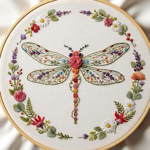 May include: An embroidered hoop art piece with a dragonfly design. The dragonfly's wings are intricately detailed with floral patterns, and its body is decorated with small, embroidered flowers. A floral wreath encircles the dragonfly, enhancing the decorative effect.