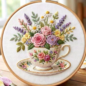 May include: Embroidered floral design in a wooden hoop. A teacup overflowing with roses, daisies, and lavender is the focal point. The teacup and saucer are intricately detailed. Embroidery threads and scissors are in the foreground.