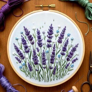 Puede incluir: Un bastidor de bordado hecho a mano con un diseño de campo de lavanda. La obra de arte presenta flores de lavanda moradas, detalles blancos y azules, y tallos verdes sobre una tela blanca. El bastidor de madera es visible, junto con carretes de hilo y tijeras.