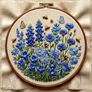 May include: A handcrafted embroidery hoop featuring a vibrant floral design. The artwork showcases blue flowers, including lupines and cornflowers, with green leaves and buzzing bees. Butterflies add a delicate touch to the botanical scene, all set against a neutral fabric background.