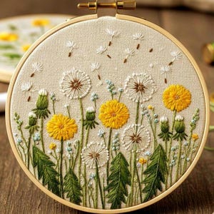May include: Embroidered dandelion design in a wooden embroidery hoop. The artwork features yellow and white dandelions with green stems and leaves, set against a beige fabric background. The hoop is secured with a brass screw.