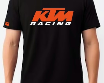 Puede incluir: Camiseta negra con un logotipo naranja de KTM Racing.