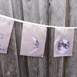 K&ouml;nnte beinhalten: Ein braunes Papierbanner mit dem Text "The moon taught me there is beauty in darkness, too." und vier Illustrationen des Mondes in verschiedenen Phasen.