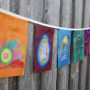 Peut inclure: Une guirlande de petits drapeaux rectangulaires avec des motifs variés, suspendus à un ruban blanc. Les drapeaux présentent de l'art abstrait aux couleurs vives et sont accrochés sur un fond en bois vieilli. Un objet décoratif.