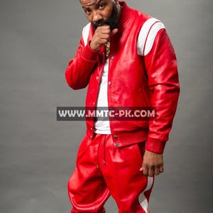 Pu&ograve; includere: Giacca in pelle rossa con strisce bianche sulle spalle e pantaloni in pelle rossi abbinati con strisce bianche laterali. L'outfit &egrave; abbinato a scarpe da ginnastica bianche. L'indirizzo del sito web "WWW.MMTC-PK.COM" &egrave; visibile.