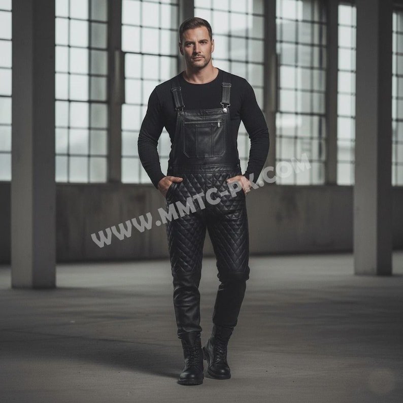 May include: Black leather overalls with a quilted pattern on the legs. The overalls have a bib with a pocket and adjustable straps. The person is wearing a black long-sleeve shirt and black boots. The background is a large industrial space with large windows.