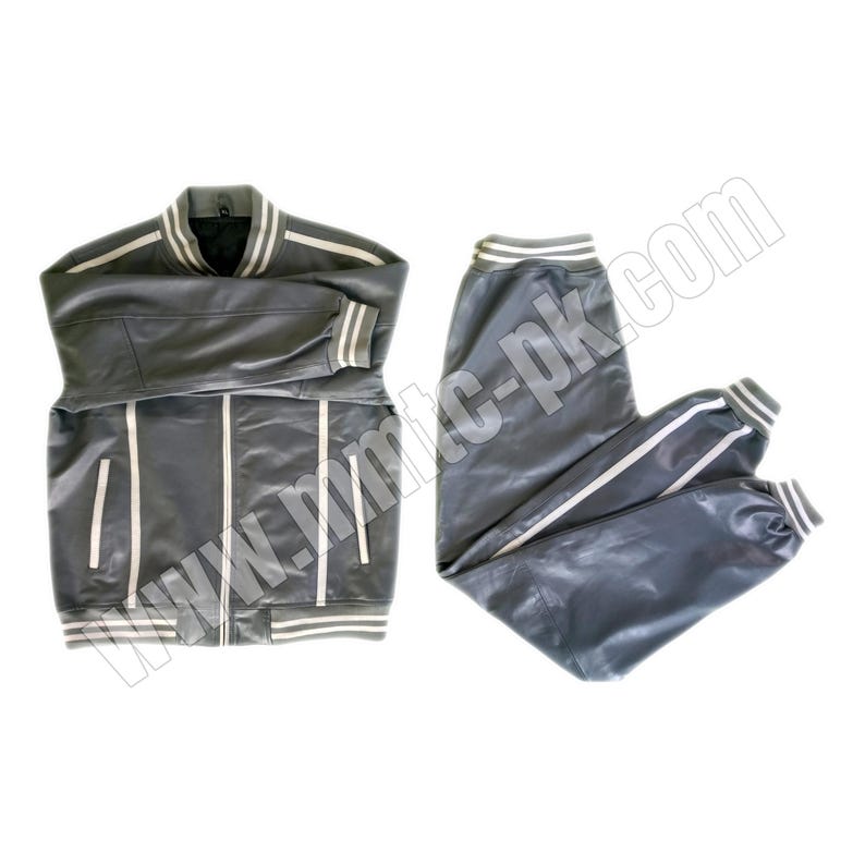 Puede incluir: Un ch&aacute;ndal de cuero gris con rayas blancas en las mangas y las piernas. La chaqueta tiene una cremallera y un cuello de canal&eacute;. El pantal&oacute;n tiene una cintura el&aacute;stica.