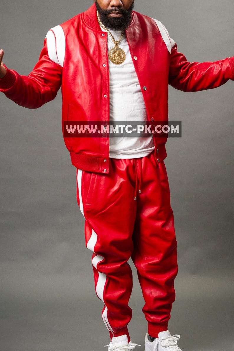 Pu&ograve; includere: Un completo in pelle rossa composto da un bomber con dettagli bianchi sulle spalle e pantaloni abbinati con strisce bianche laterali. L'outfit include una maglietta bianca e scarpe da ginnastica bianche. &Egrave; visibile anche una catena d'oro con un ciondolo.