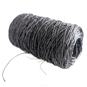 May include: A spool of dark gray twine, tightly wound and textured. The twine appears to be made of natural fibers, with a slightly uneven surface. The spool is set against a white background, highlighting the color and texture of the twine.