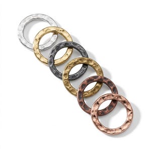 May include: A set of six circular metal rings arranged in a diagonal line. The rings feature a hammered, textured surface and come in various metallic finishes including silver, gold, dark charcoal, brass, copper, and rose gold tones.