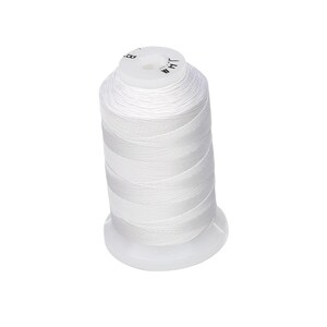 May include: A spool of white thread, tightly wound around a white plastic base. The thread is smooth and appears to be a medium weight. The top of the spool has the word "WHT" printed on it.