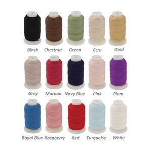 May include: A selection of thread spools in a range of colours: black, chestnut, green, ecru, and gold. Other colours include grey, maroon, navy blue, pink, and plum. The image also shows royal blue, raspberry, red, turquoise, and white thread spools.