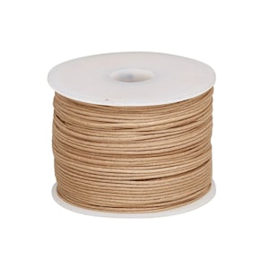 May include: A spool of light tan cord wrapped tightly around a white plastic cylinder. The cord is thin, smooth, and uniform in colour, wound in multiple horizontal layers covering the entire height of the spool from top to bottom edge.