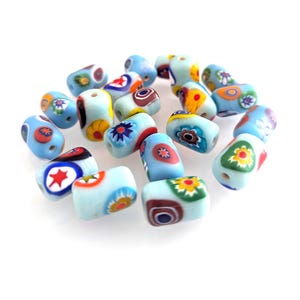 May include: A selection of light blue glass beads, each adorned with vibrant floral and geometric patterns. The beads are cylindrical with rounded edges, showcasing red, yellow, and white details. Perfect for jewellery making and various craft projects.