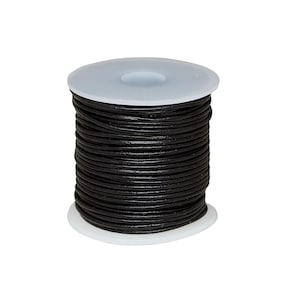 May include: A spool of black leather cord wrapped tightly around a white plastic cylinder. The cord has a smooth, rounded texture and is wound in multiple horizontal layers from the top to the bottom of the spool, creating a uniform stack.