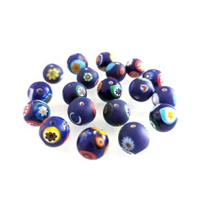 Pode incluir: Um conjunto de contas de vidro azul escuro com desenhos florais coloridos. Cada conta apresenta um padrão único de flores e formas em tons de amarelo, vermelho, verde e branco. As contas são redondas e têm um furo para enfiar.