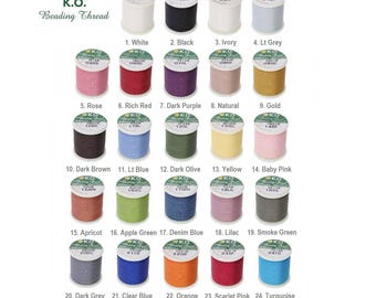 May include: A color chart of 24 spools of K.O. Beading Thread. The spools are arranged in four rows of six spools each. Each spool is labeled with a number and the color name. The colors include white, black, ivory, light grey, rose, rich red, dark purple, natural, gold, dark brown, light blue, dark olive, yellow, baby pink, apricot, apple green, denim blue, lilac, smoke green, dark grey, clear blue, orange, scarlet pink, and turquoise.