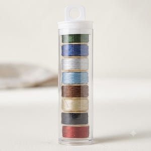 May include: A clear plastic cylindrical storage tube containing eight stacked spools of sewing thread in various colors including dark green, navy blue, silver, light blue, brown, beige, black, and deep red, topped with a white hanging cap.