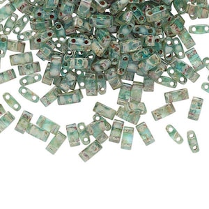 May include: A collection of rectangular two-hole beads in a translucent seafoam green color with an iridescent finish. Each bead features a smooth, slightly rounded surface and two parallel holes drilled through the center for threading.