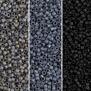 Op de afbeelding: Drie verticale panelen met kleine, cilindrische kralen in verschillende tinten. Het linkerpaneel toont kralen in een gedempt, metallic grijs. Het middelste paneel toont kralen in een donkerder, leisteen grijs. Het rechterpaneel toont zwarte kralen.