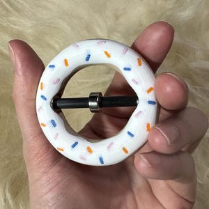 May include: White donut-shaped belt buckle with blue, orange, and pink sprinkles.
