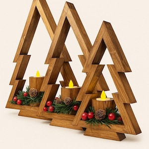 May include: Wooden Christmas tree candle holders. Each tree-shaped holder has a candle, pinecones, red berries, and greenery. The candle flames are yellow. The wood has a warm brown tone.