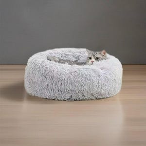 May include: A gray fluffy pet bed with a cat curled up inside. The bed is round and has a raised edge.