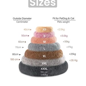 May include: A chart showing the different sizes of pet beds, with the outside diameter in centimeters and the recommended weight of the pet in kilograms. The sizes are XS, S, M, L, XL, XXL, and XXXL. The chart is made up of a stack of different colored pet beds.