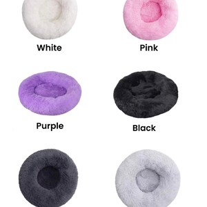 May include: Six different colors of round pet beds. The beds are made of soft, fluffy material and have a raised rim. The colors are white, pink, purple, black, dark gray, and light gray.