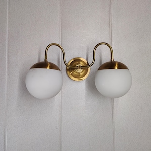Modern Brass Wall Sconce with Double Globes, Elegant Vanity Light, Contemporary Bathroom Wall Lamp, Gold Mirror Fixture, and Glass Lighting.
