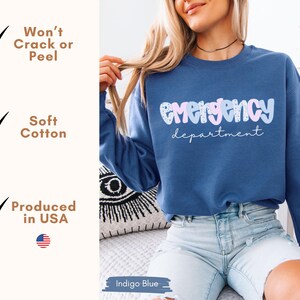May include: Indigo blue sweatshirt with the words "Emergency department" in a bubble font. The text is in light blue and pink. The sweatshirt is made of soft cotton and produced in the USA.