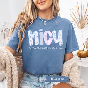 Peut inclure: T-shirt bleu jean avec les lettres "NICU" dans un motif floral et vichy. Les mots "neonatal intensive care unit" sont imprim&eacute;s en dessous. Le t-shirt &agrave; manches courtes a une coupe d&eacute;contract&eacute;e.