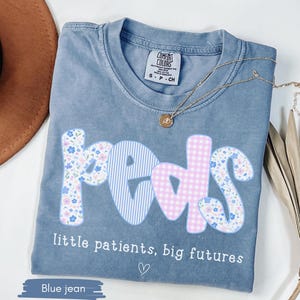 blue Comfort Colors® shirt with pastel floral and gingham “peds” design and phrase “little patients, big futures,” styled with necklace