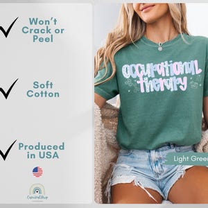 Op de afbeelding: Lichtgroen t-shirt met de tekst "Occupational Therapy" in een pastelkleurig ontwerp. Het shirt is gemaakt van zacht katoen en geproduceerd in de VS. De tekst "Won't Crack or Peel" is ook zichtbaar.