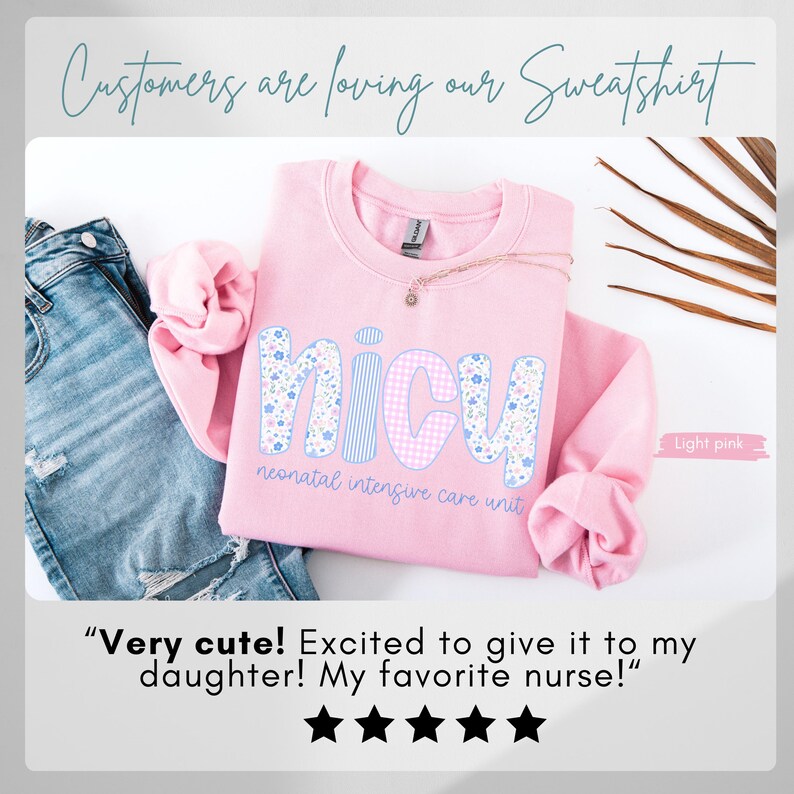 Op de afbeelding: Lichtroze sweatshirt met de letters "NICU" in bloemen- en ruitpatroon. De tekst "NICU neonatal intensive care unit" staat op de voorkant. De afbeelding bevat ook een spijkerbroek en een gouden ketting.