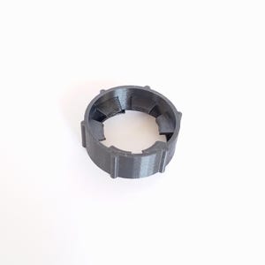 Puede incluir: Un anillo de plástico negro con un borde exterior acanalado y una serie de crestas internas. El anillo está diseñado para ajustarse alrededor de una botella o un frasco.