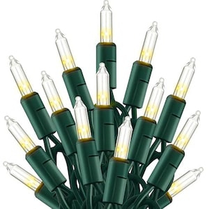May include: A string of clear incandescent mini lights featuring small glass bulbs attached to dark green plastic sockets and wiring. The lights emit a warm yellow glow, arranged in a cluster with multiple bulbs pointing outward.