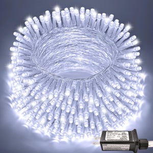 May include: A coil of bright white LED string lights featuring numerous small, clear bulbs emitting a cool glow. A black electrical plug with a rectangular controller box is attached, displaying technical specifications and safety text.