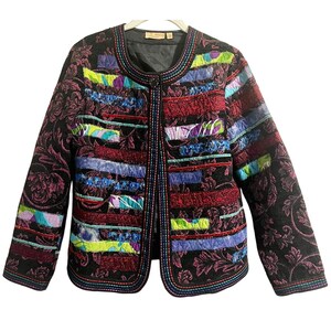 May include: A quilted jacket with a black floral pattern and colorful horizontal stripes in red, blue, purple, and green. The jacket has a round neckline and is lined with black fabric. The edges are trimmed with colorful stitching.