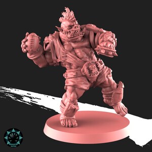 Peut inclure: Figurine d'orc muscl&eacute; de couleur rose, en position de joueur de football am&eacute;ricain, tenant un ballon. L'orc a une cr&ecirc;te, des d&eacute;fenses et porte des &eacute;pauli&egrave;res, une ceinture avec une boucle en forme de cr&acirc;ne et une armure de jambe. La figurine est sur une base ronde.