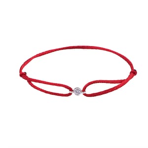 Könnte beinhalten: Ein rotes Armband mit einem kleinen, klaren Diamanten, der in einen silbernen Verschluss gefasst ist.